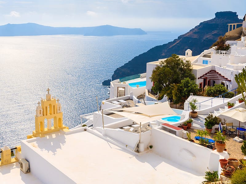 The yellow bell tower of Firostefani on the caldera edge, with a cruise ship in the bay