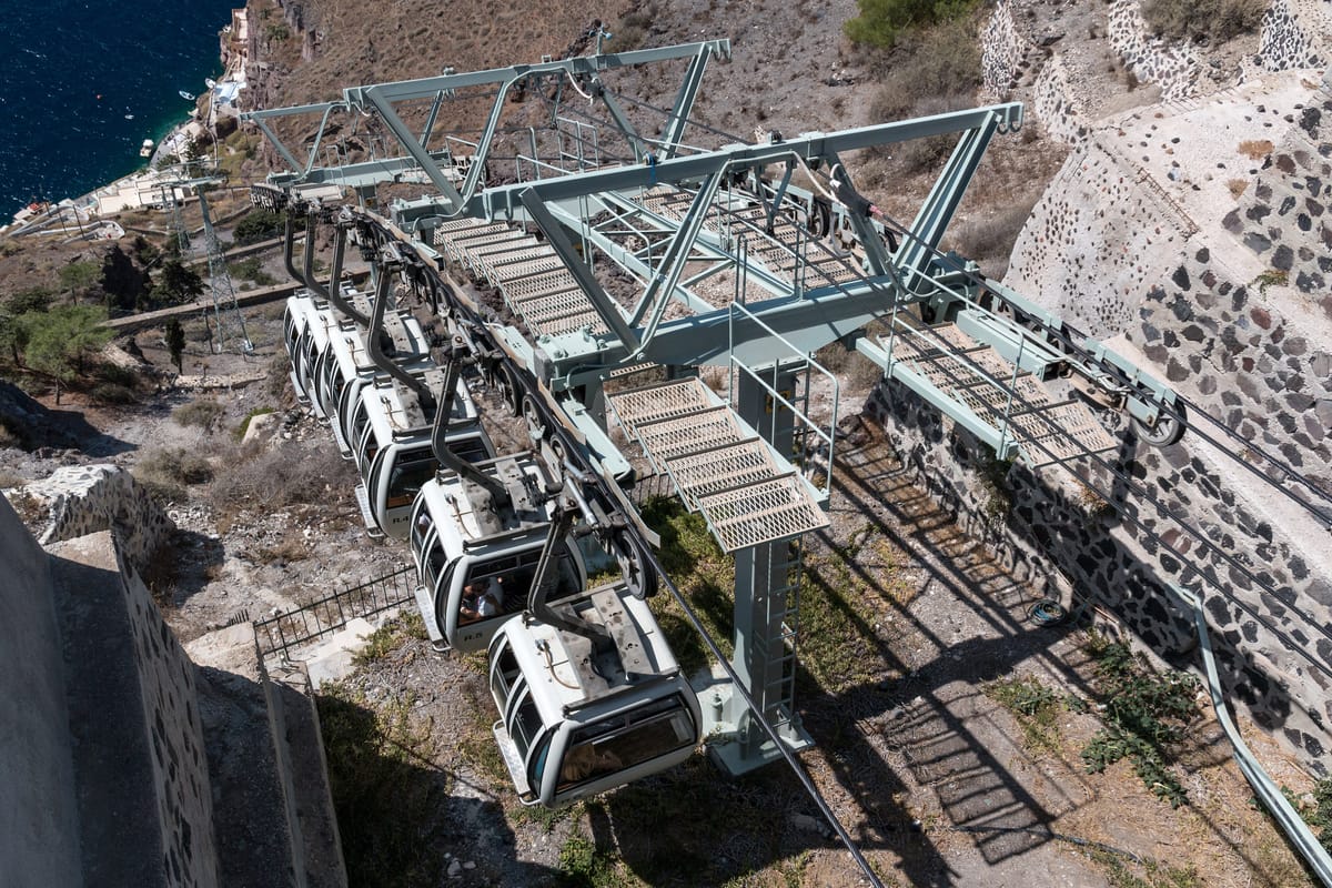 The top station of the Fira cable car: the cabins at the platform, the old port far below
