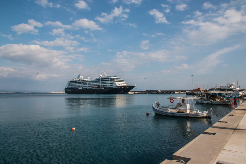 The cruise pier of Katakolo from the village quay: a ship alongside, fishing boats in the foreground