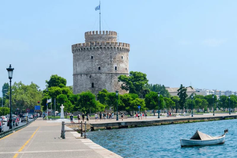 The White Tower of Thessaloniki on the waterfront, with a boat on the water in front of it